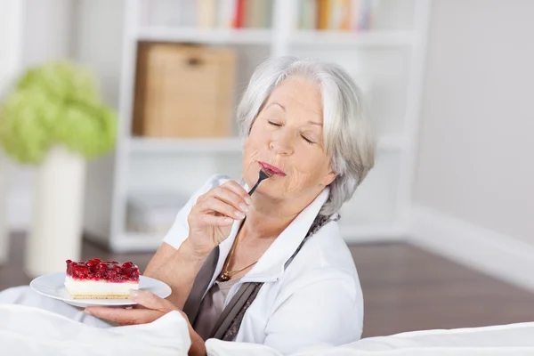 Старший женщина наслаждаясь фруктовым кремом торт — стоковое фото