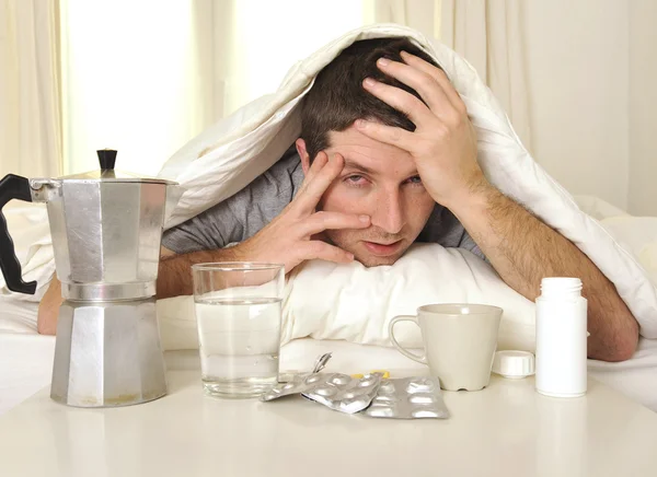 Человек с головной боли и похмелья в постели с аксессуарами — стоковое фото