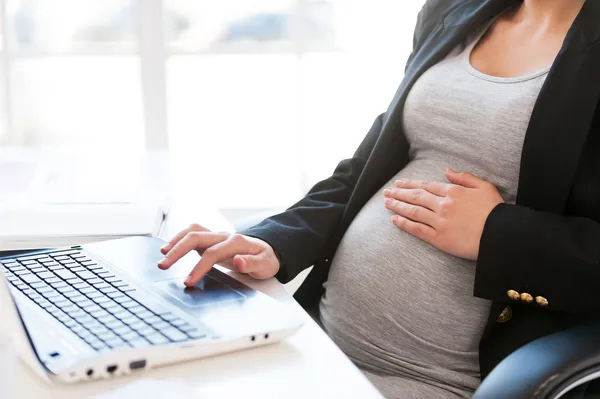 Беременная женщина, работает на ноутбуке — стоковое фото