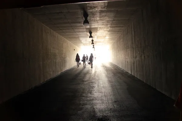 Люди ходят через темный тоннель — стоковое фото
