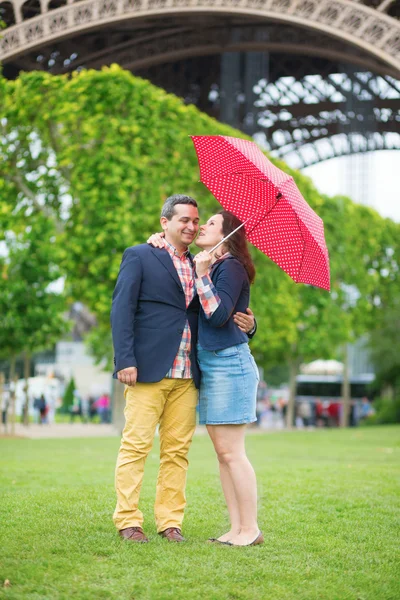 Пара под красный зонт возле Эйфелевой башни — стоковое фото