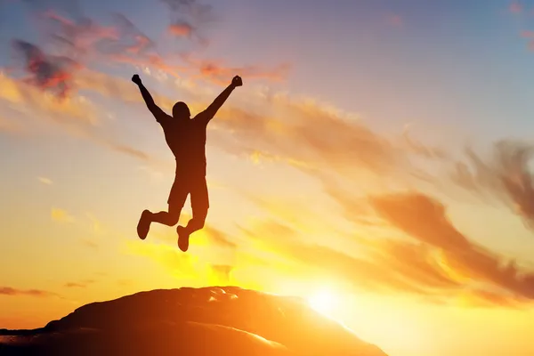 Человек прыгает от радости на пике горы — стоковое фото