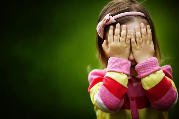Маленькая девочка играет лицо сокрытия пряток — стоковое фото
