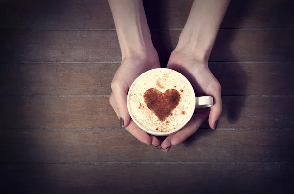 Женщина держит чашку горячего кофе, с формы сердца — стоковое фото