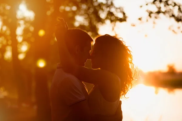 Молодая красивая пара, охватывающей на белом фоне заката Лицензионные Стоковые Фото