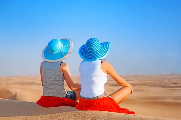 Две девушки в шляпах расслабляющий в пустыне — стоковое фото