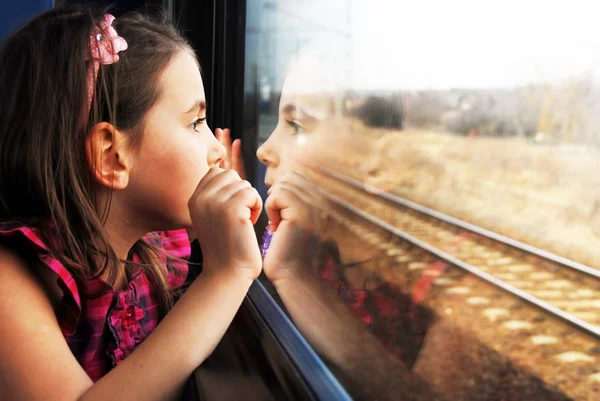 Маленькая девочка, глядя через окно. Она путешествует на поезде Стоковое Изображение