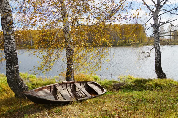 Осенние riverbank с старой деревянной лодке Лицензионные Стоковые Изображения