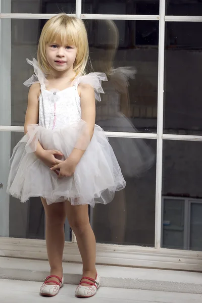 Девочка 3 лет в белом платье возле окна — стоковое фото