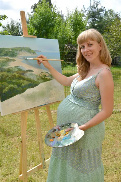 Молодых беременных женщин художник рисует картину масляными красками в t — стоковое фото