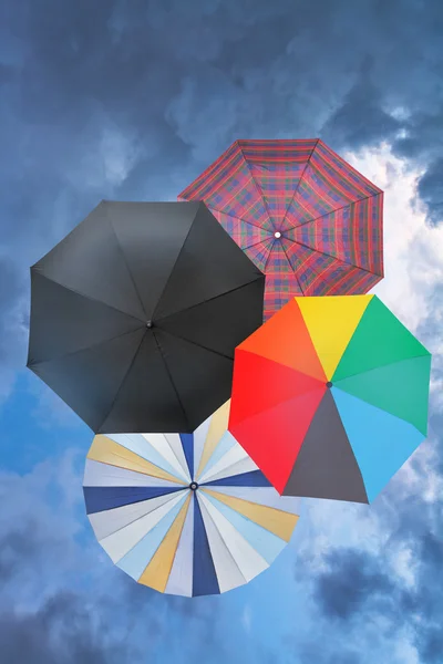 Четыре открытых зонтики с голубой дождливые облака Стоковое Изображение