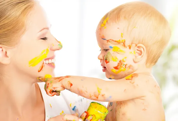 Счастливый грязный ребенок рисует красками на лице матери — стоковое фото