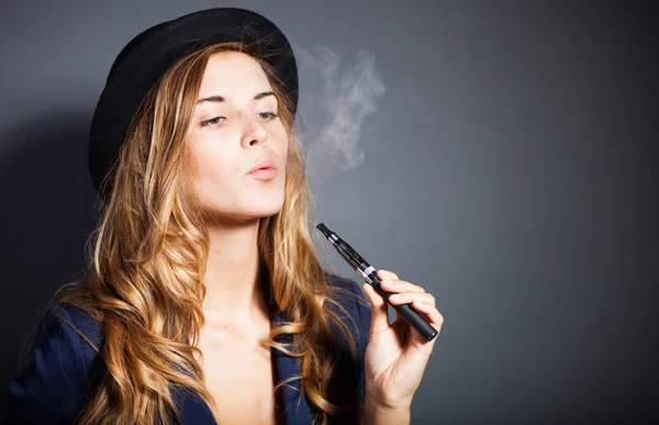 Элегантная женщина курить e сигареты с дымом носить костюм и шляпа — стоковое фото