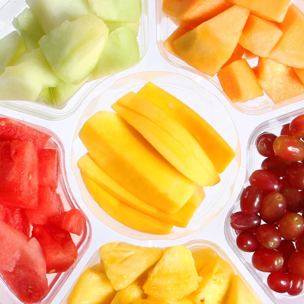 Свежие куски фруктов в пластиковый контейнер. здоровый образ жизни. различные виды нарезанных фруктов: манго, арбуз, дыня, виноград, ананас — стоковое фото