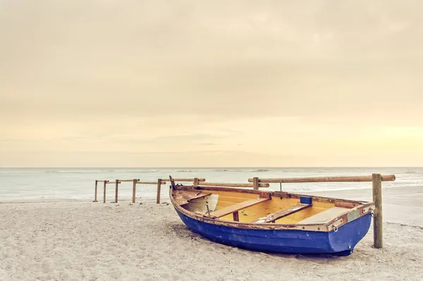 Старый желтый синий деревянные лодки на белом пляже на теплый закат Стоковое Фото