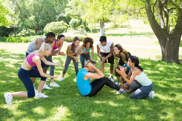 Друзья аплодисменты человек делает sit ups — стоковое фото