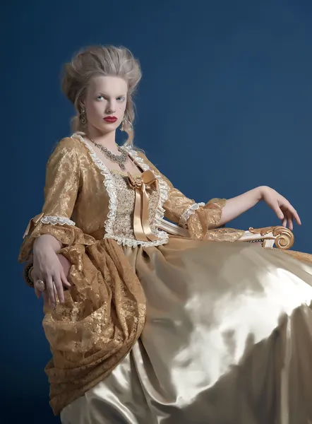 Ретро мода барокко женщины носили золотые платья. сидя на винта — стоковое фото