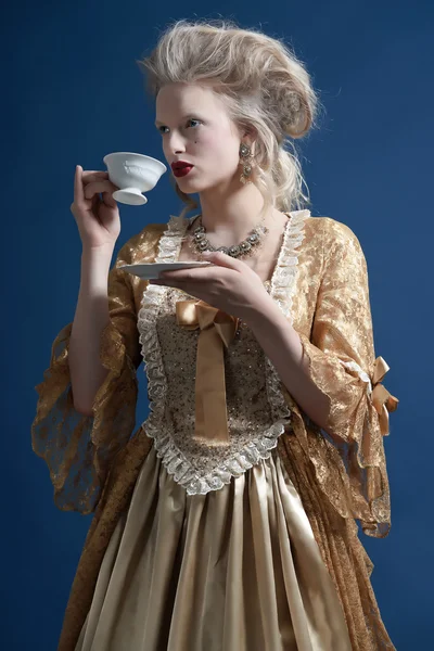 Ретро мода барокко женщины носили золотые платья. держа чашку — стоковое фото