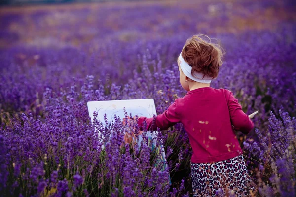 Маленькая девочка рисует картину в лавандового поля — стоковое фото