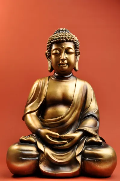Бронзовая статуя Будды на красном фоне оранжевый Лицензионные Стоковые Изображения