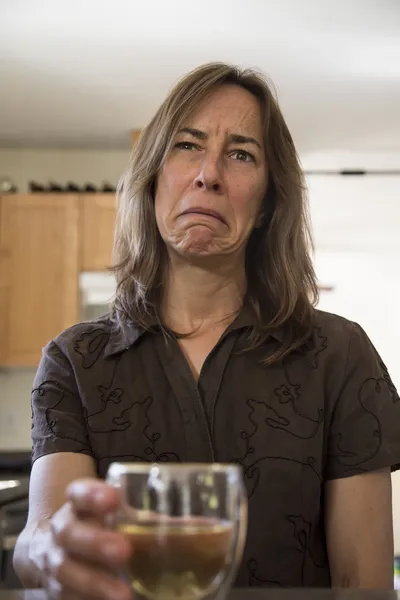 Несчастной среднего возраста женщина на кухне, пьет вино — стоковое фото