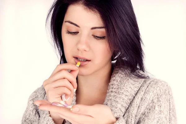 Girl holding a medicine and lozhet it in his mouth (retro) — стоковое фото