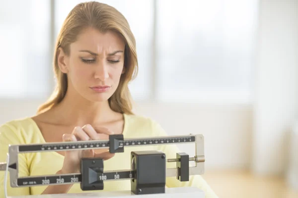 Женщина с использованием баланса вес масштаба в тренажерном зале Стоковое Фото