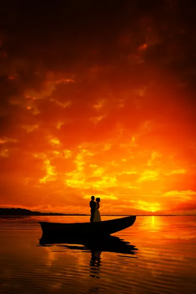 Силуэт пару поцелуи в лодке на реке в закат Лицензионные Стоковые Фото