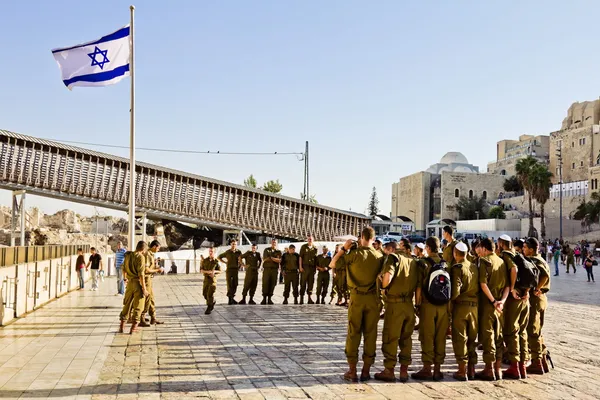 A squad of Israeli soldiers on the square near the Western Wall under national flag (Jerusalem) — стоковое фото
