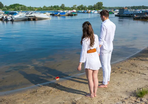 Мужчина и женщина, стоя на берегу реки банка и провожать игрушка лодка wi — стоковое фото