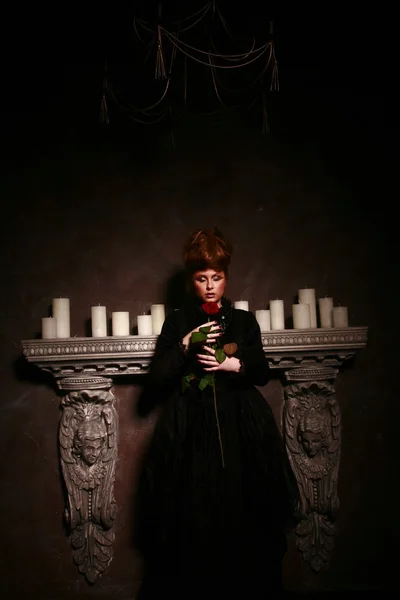 Готическая девушка, стоя возле свечи с красной розы — стоковое фото