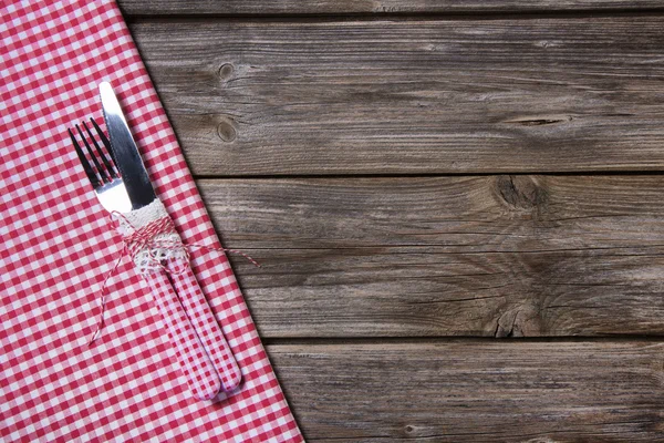 Нож и вилка в красно-белый клетчатый на деревянных фоне Лицензионные Стоковые Изображения