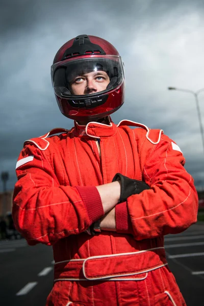 Гонщик, носить красный гоночный защитный костюм и шлем Стоковое Изображение
