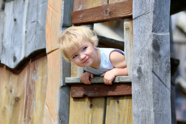 Смешная маленькая девочка, играя в деревянном доме Стоковая Картинка