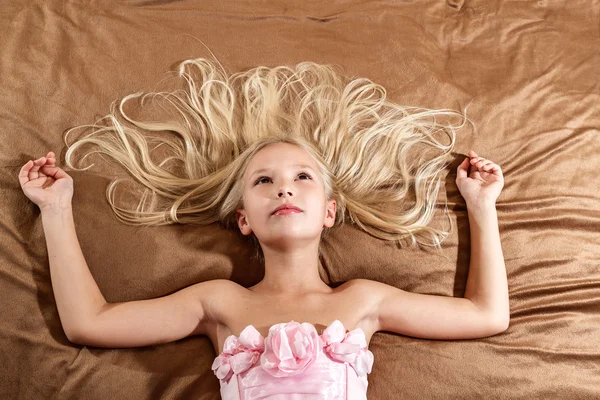 Красивая маленькая девочка, мечтает на кровати — стоковое фото