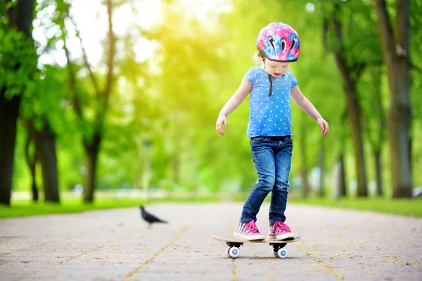 Маленькая девочка учиться скейтборд на открытом воздухе — стоковое фото