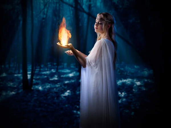 Эльфийская девушка с огнем в ночном лесу — стоковое фото