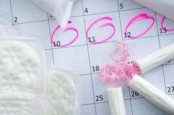 Белый календарь с розовыми круги вокруг менструации период Дата и чистой тампоны, лежал на вершине — стоковое фото