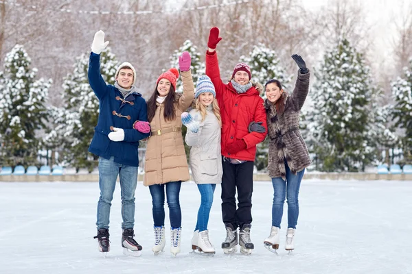 Счастливые друзья катание на коньках на катке на открытом воздухе — стоковое фото