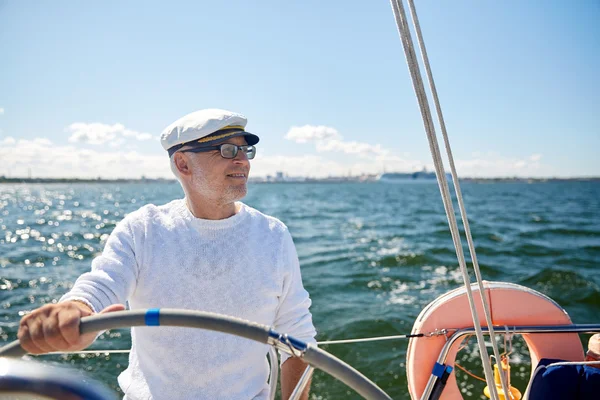 Старший мужчина у руля на парусные лодки или яхты в море — стоковое фото