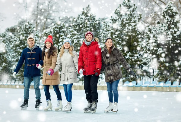 Счастливые друзья катание на коньках на катке на открытом воздухе — стоковое фото