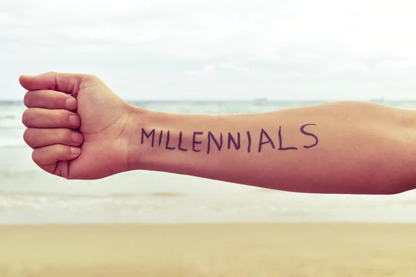 Молодой человек с millennials слова, написанные в его руке — стоковое фото