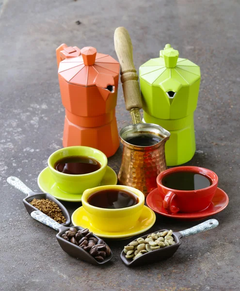 Green, black coffee beans and different utensils for boiling coffee (grinder, kettle, cezve) — стоковое фото