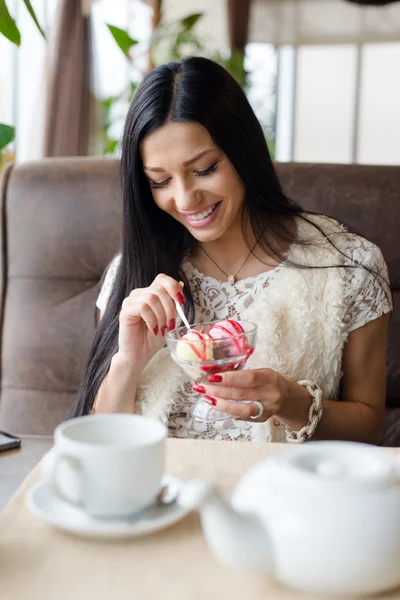 Картина Портрет крупным планом на великолепные брюнетка молодая симпатичная женщина, едят мороженое, весело счастливым, улыбаться в уютном кафе или ресторан интерьер фон — стоковое фото