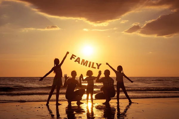 Счастливая семья, стоящая на пляже во время заката — стоковое фото