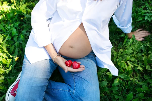 Беременная женщина, держа в руке сердца — стоковое фото
