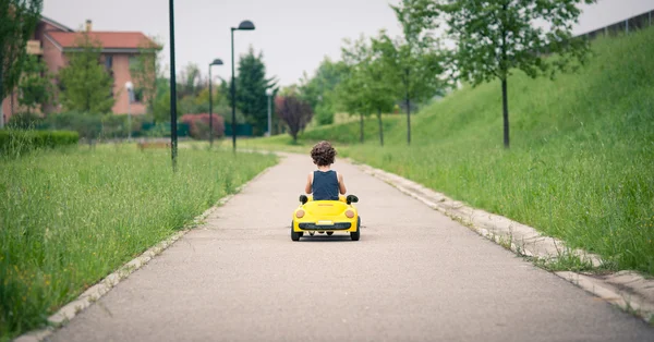 Молодой парень, играя с игрушечный автомобиль на улице — стоковое фото