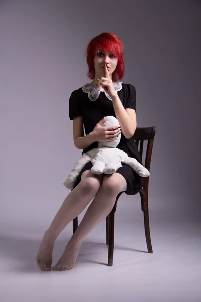 Рыжеволосая девушка и куклы на стуле — стоковое фото