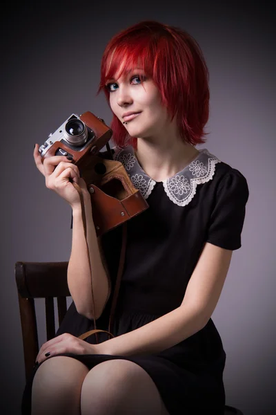 Девушка с ретро камеры на стуле — стоковое фото