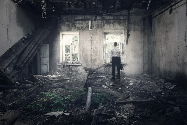 Человек вернулся в разрушенный дом — стоковое фото